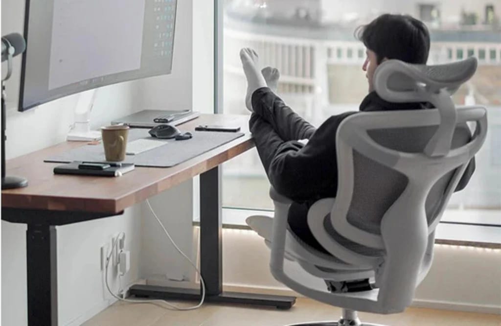Utilisateur en position inclinée sur une chaise de bureau ergonomique avec appui-tête, profitant d’un moment de détente après une longue session de travail à l’écran.