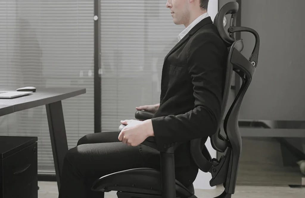 Un homme en costume est assis sur une chaise ergonomique Sihoo