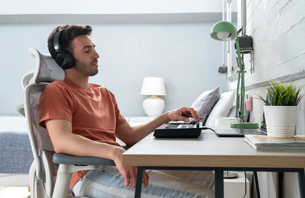 Homme composant de la musique dans son bureau à domicile, confortablement assis sur la chaise ergonomique Sihoo Doro C300 Pro blanche et grise.